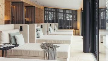 Una habitación de hotel moderna con un ventanal grande, un sofá, una pequeña mesa y una cama.