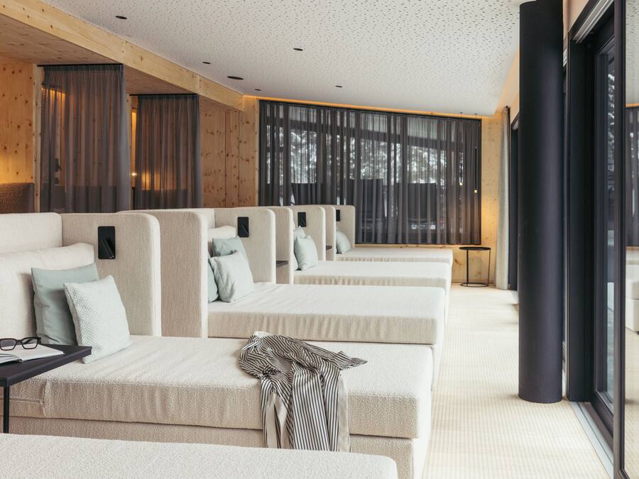 Una habitación de hotel moderna con un ventanal grande, un sofá, una pequeña mesa y una cama.