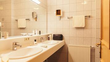 A modern bathroom with two sinks, a mirror, a towel rack, and a radiator.
