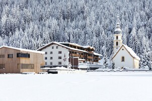Un hotel con fachada de madera, un restaurante-bar y una iglesia con campanario.