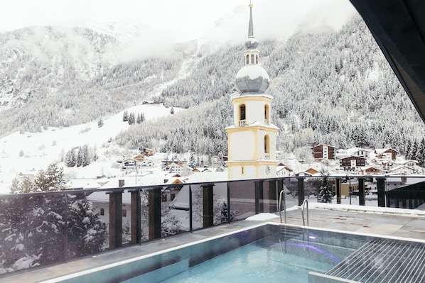 Un paisaje montañoso cubierto de nieve con una torre de iglesia y edificios residenciales.