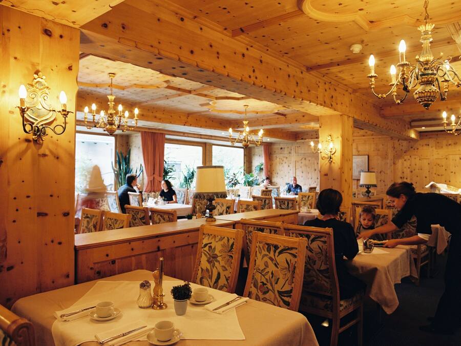 Ein gemütliches Restaurant mit Holzvertäfelungen, mehreren Tischen und Kronleuchtern.
