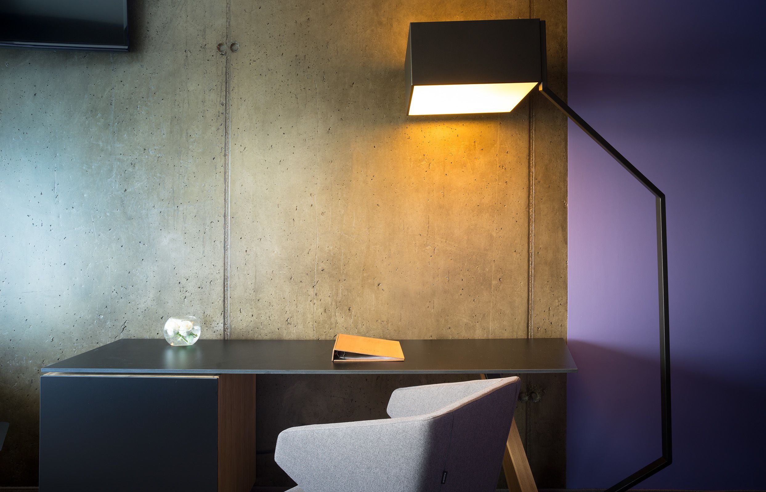 A modern desk with a lamp, a chair, and a small decorative item on the desk.