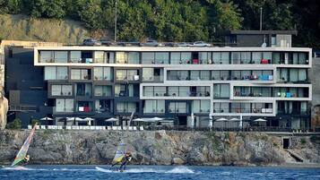 A multi-story hotel with balconies, located near a rocky coastline.