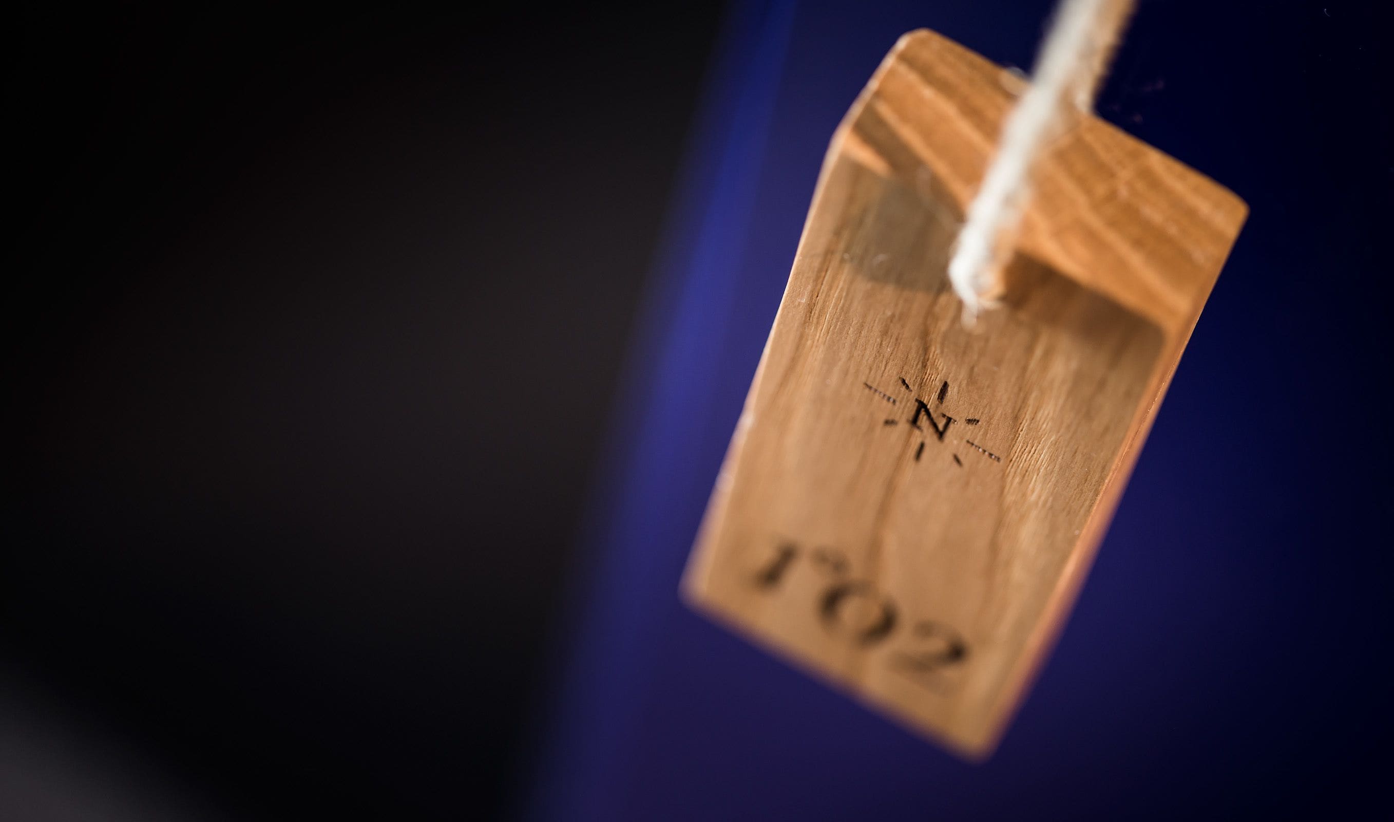 A wooden tag with a compass and the number 1702.