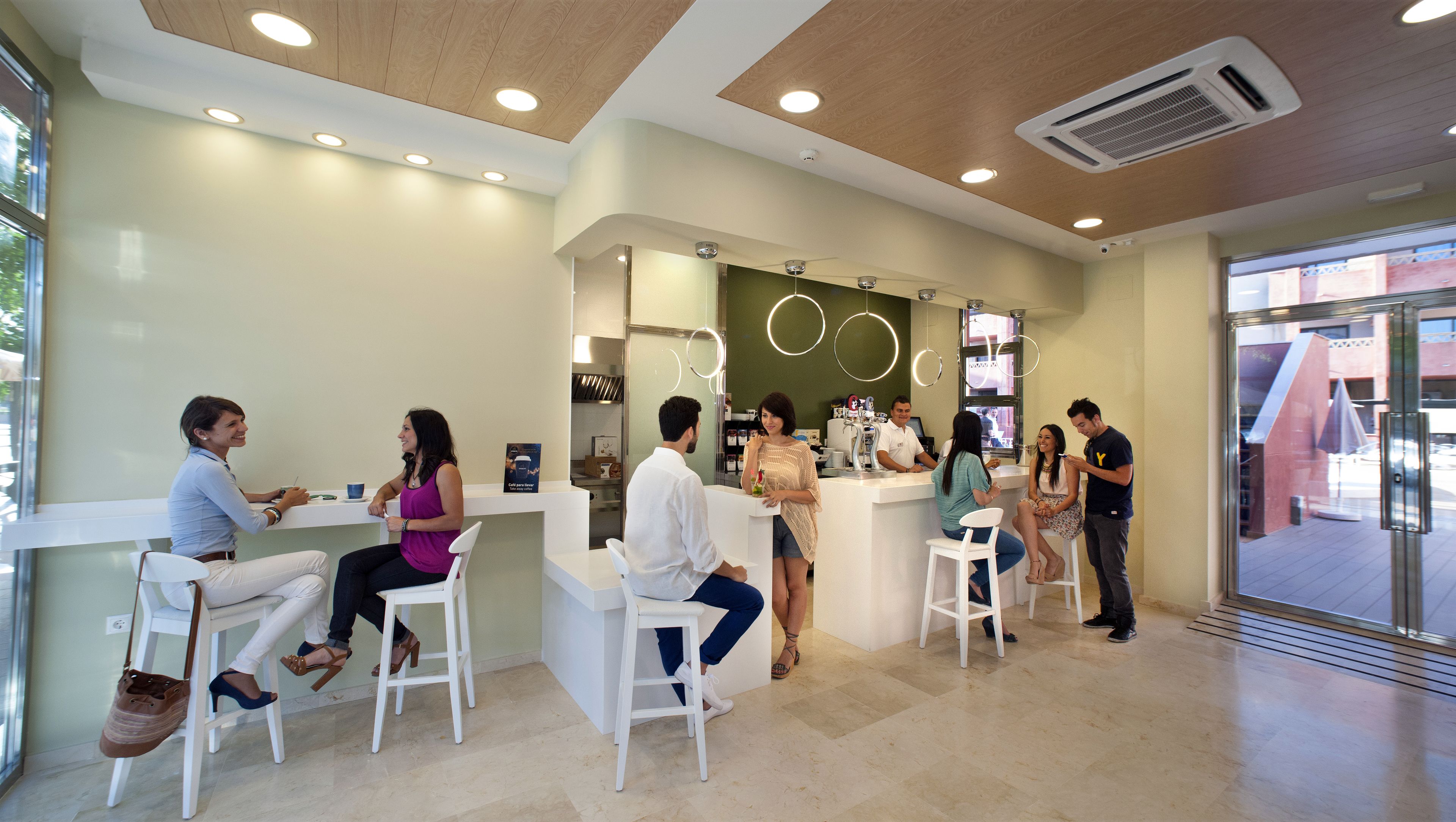 A modern interior with white furniture, a reception desk, and a visible air conditioning unit.