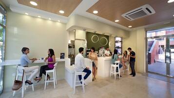 A modern interior with white furniture, a reception desk, and a visible air conditioning unit.