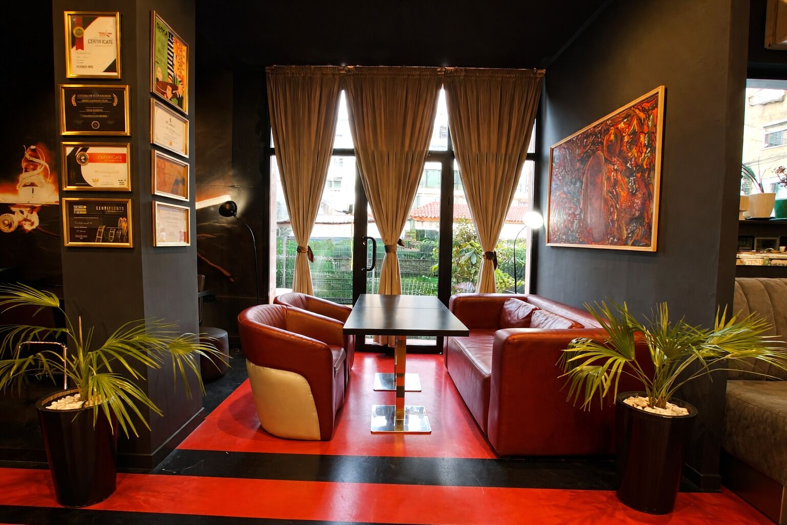 Un interior moderno con alfombra roja, sofás de cuero, una mesa y plantas en macetas.