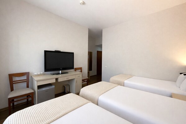 A hotel room with a desk, television, two beds, and a chair. - Signature Idea Hotel  (Tirana)