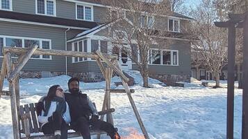 A wooden swing set and a fire pit in a snowy outdoor area.