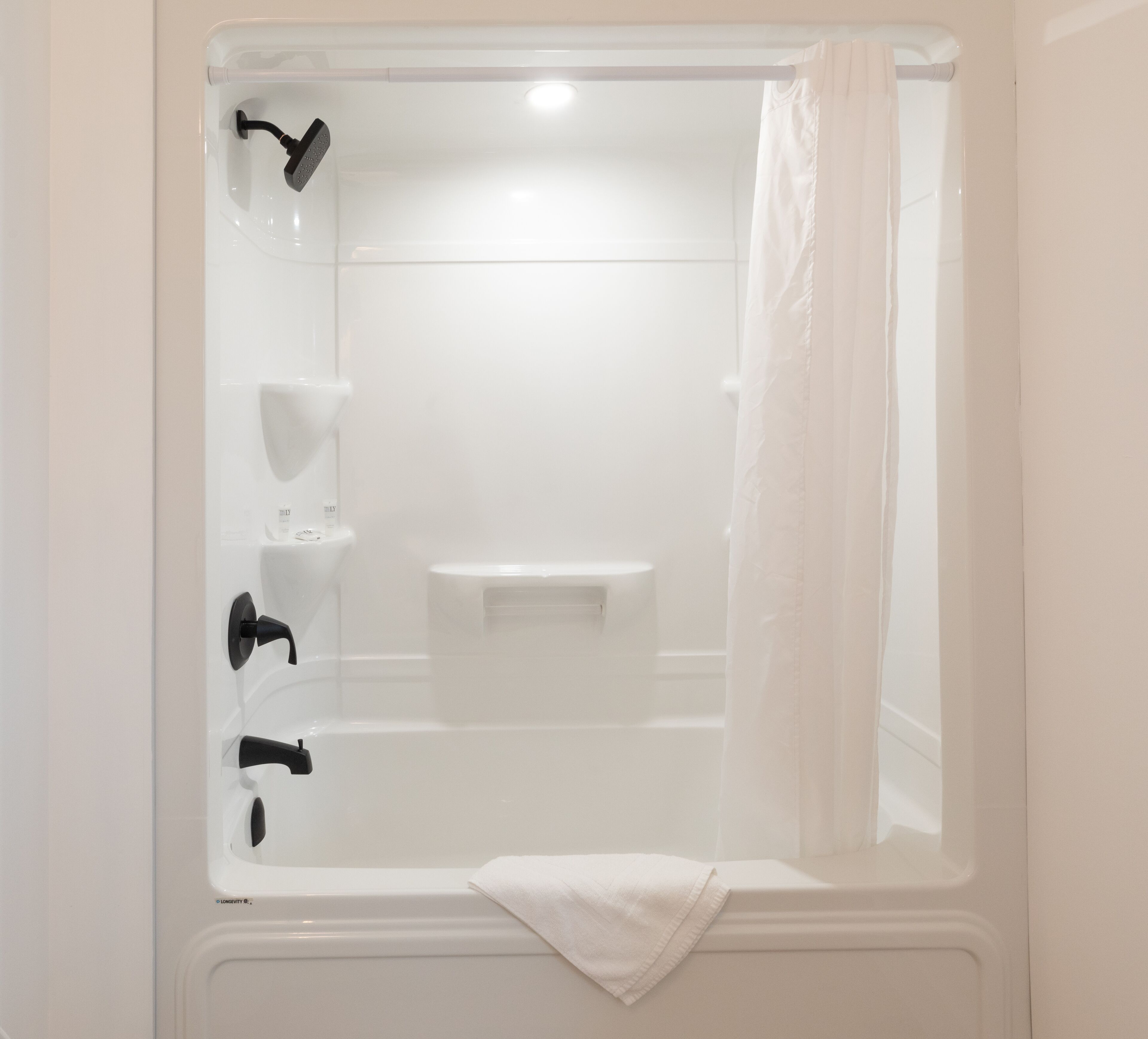 Un baño blanco con bañera, ducha e inodoro.
