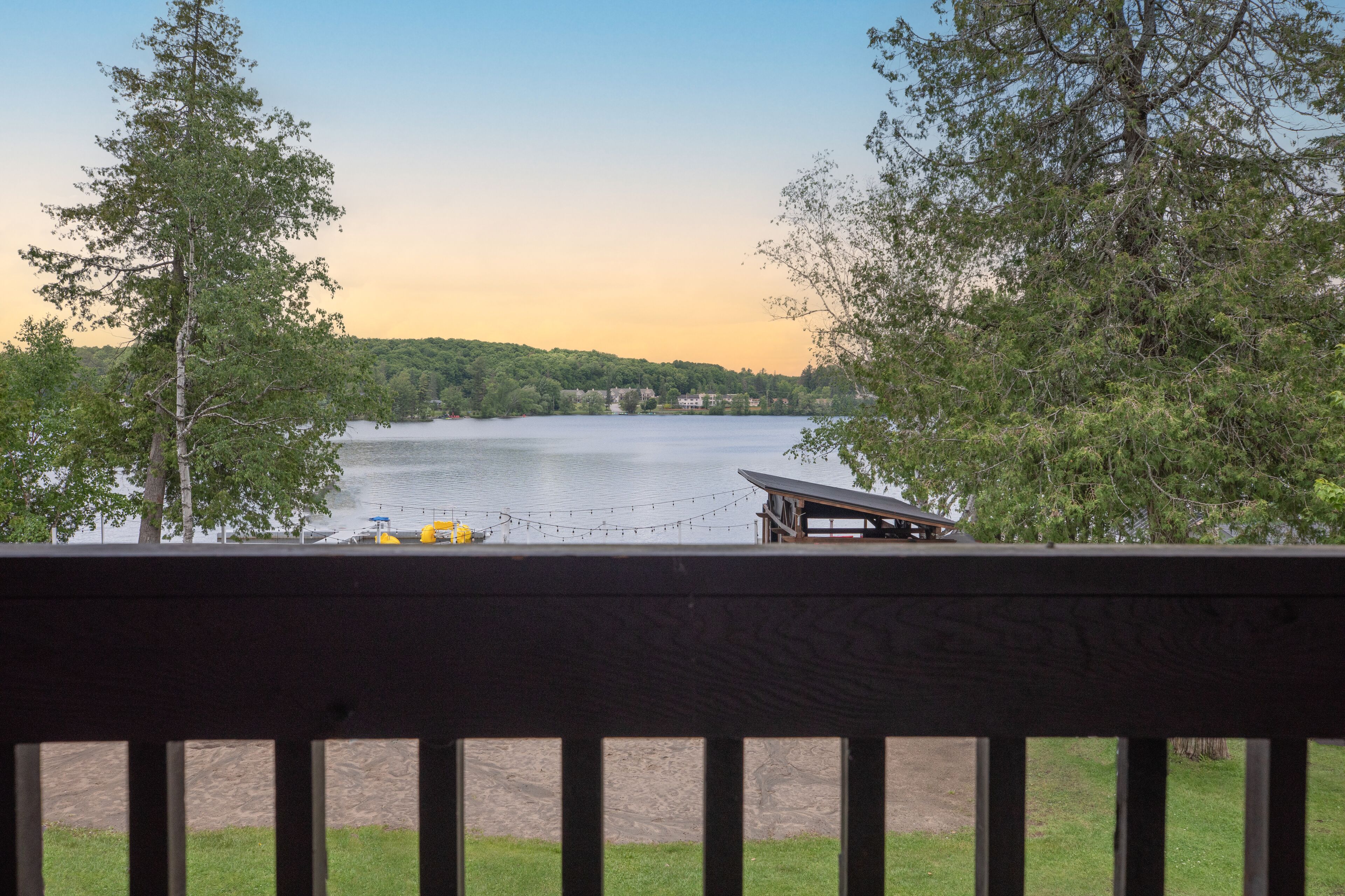 Une vue sur le lac depuis une terrasse en bois, avec un bateau amarré à proximité.