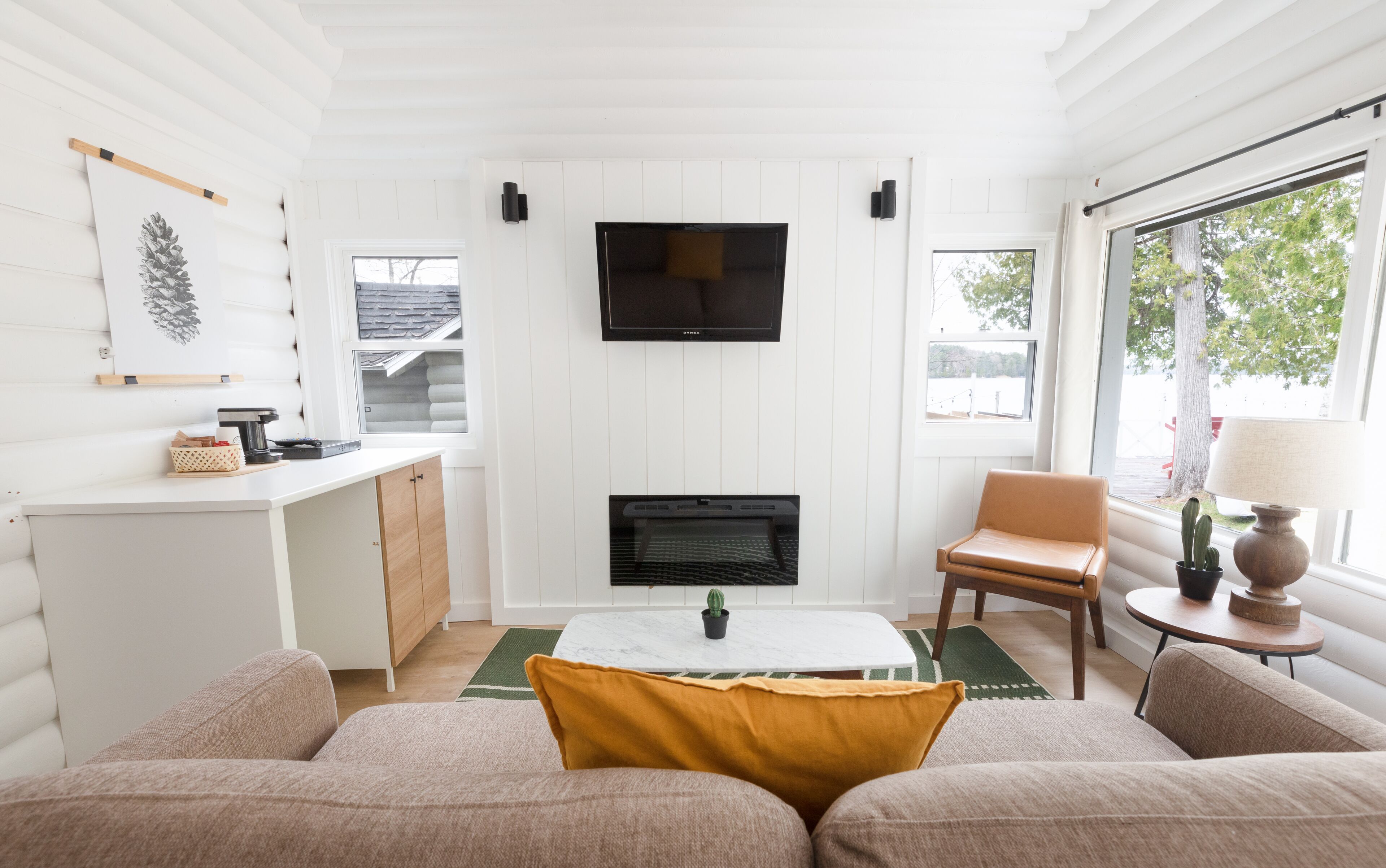 A cozy living room with a fireplace, a television mounted on the wall, and a comfortable seating area with a sofa and armchairs.