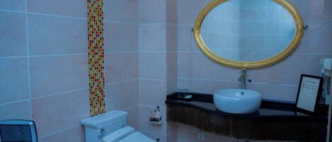 Un baño con inodoro, lavamanos y espejo.