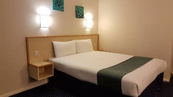 A hotel room with a bed, nightstand, two wall-mounted lights, and two wall art pieces.