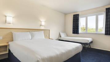 Habitación de hotel con una cama grande, una cama más pequeña, una ventana con cortinas y dos luces fijadas a la pared.