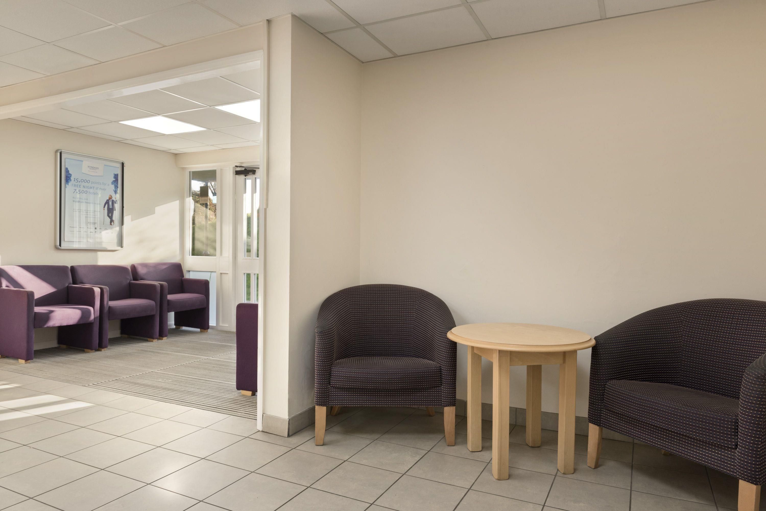 A reception area with a seating arrangement, a small table, and a poster on the wall.
