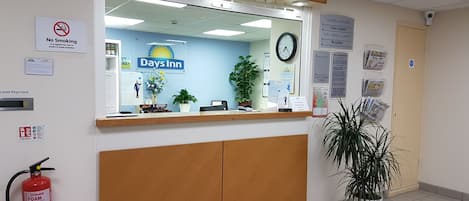 A reception desk with a clock, a 'No Smoking' sign, a 'Days Inn' sign, and a fire extinguisher.