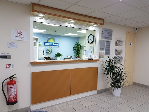 En reception med et ur, et 'Røgfri'-skilt, et 'Days Inn'-skilt og en brandslukker.