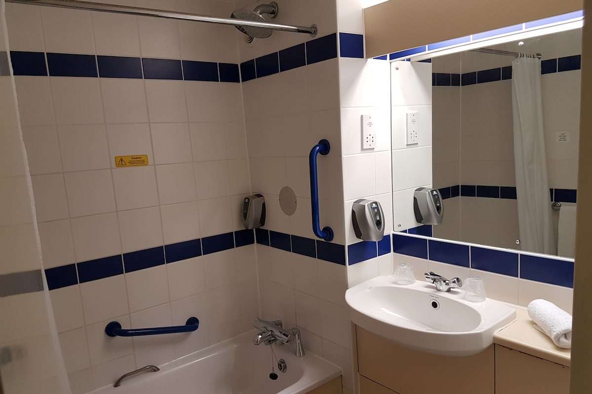 Et badeværelse med badekar, vask og spejl.