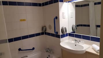 A bathroom with a bathtub, a sink, and a mirror.