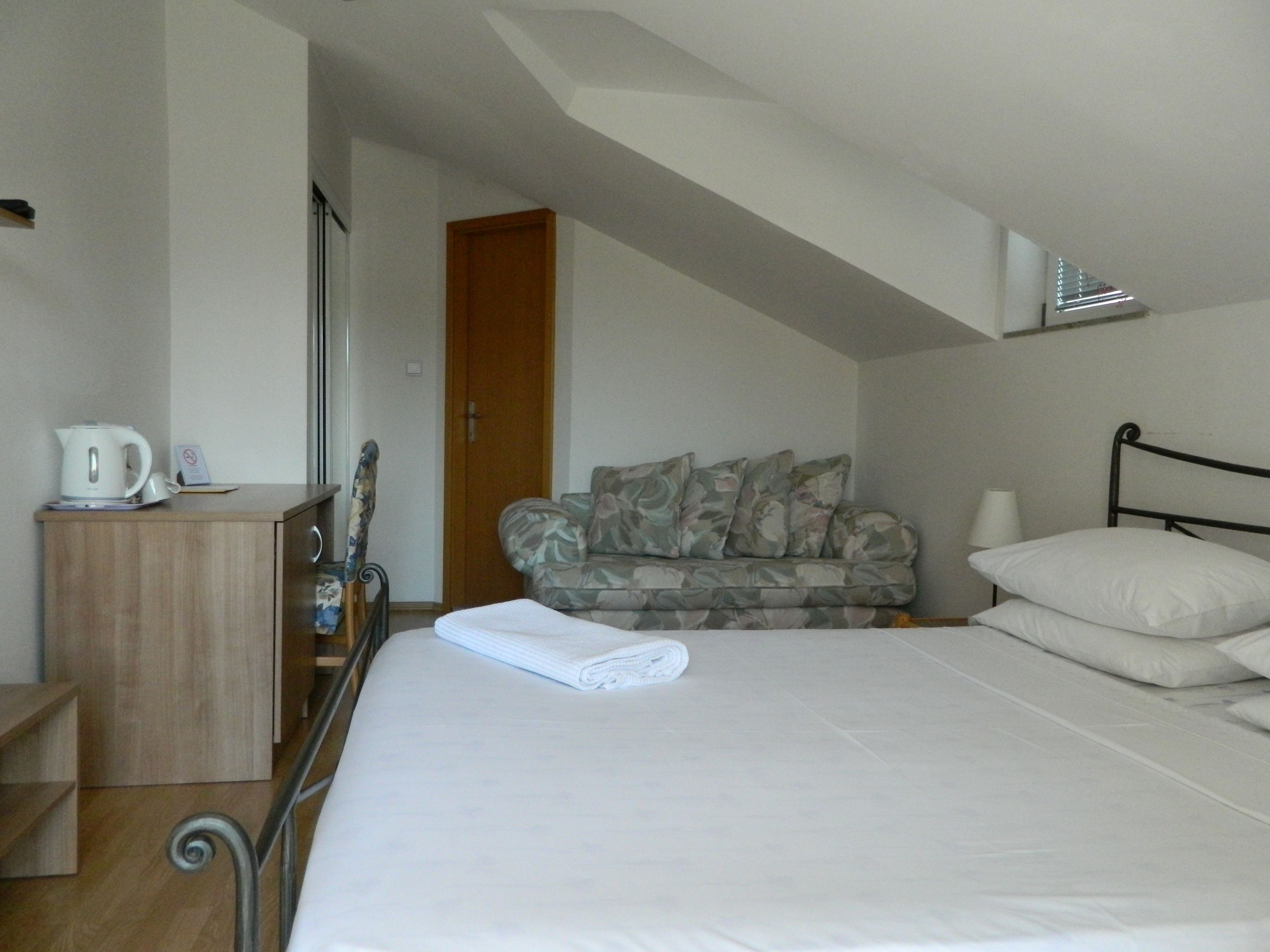Ein Schlafzimmer mit einem Bett, einem Holzschrank, einem Heizkörper und einer Tür zu einem anderen Raum.