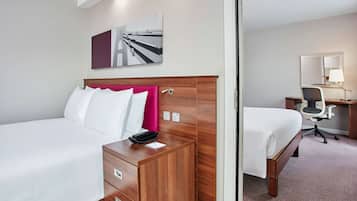 A hotel room with two beds, a desk, a chair, and a mirror.