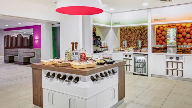 Ein modernes Café mit zentraler Theke, Sitzbereich und einer Juice Bar.