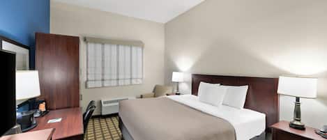 Habitación de hotel con cama, mesitas de noche, escritorio, silla, televisor y ventana con persianas.