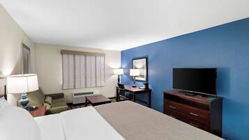 A hotel room with a bed, a desk, a chair, a television, and a window with curtains.