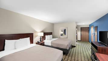 Habitación de hotel con dos camas, un escritorio con computadora, un televisor y un cuadro en la pared.