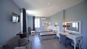 A hotel room with a sofa, two beds, a desk, and a TV. - Splendid Hotel (L'Île-Rousse)