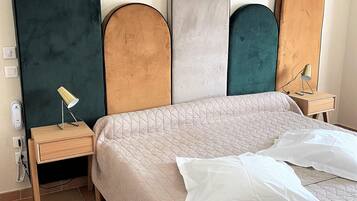 A bedroom with a bed, a nightstand, a lamp, and a wall-mounted light fixture.