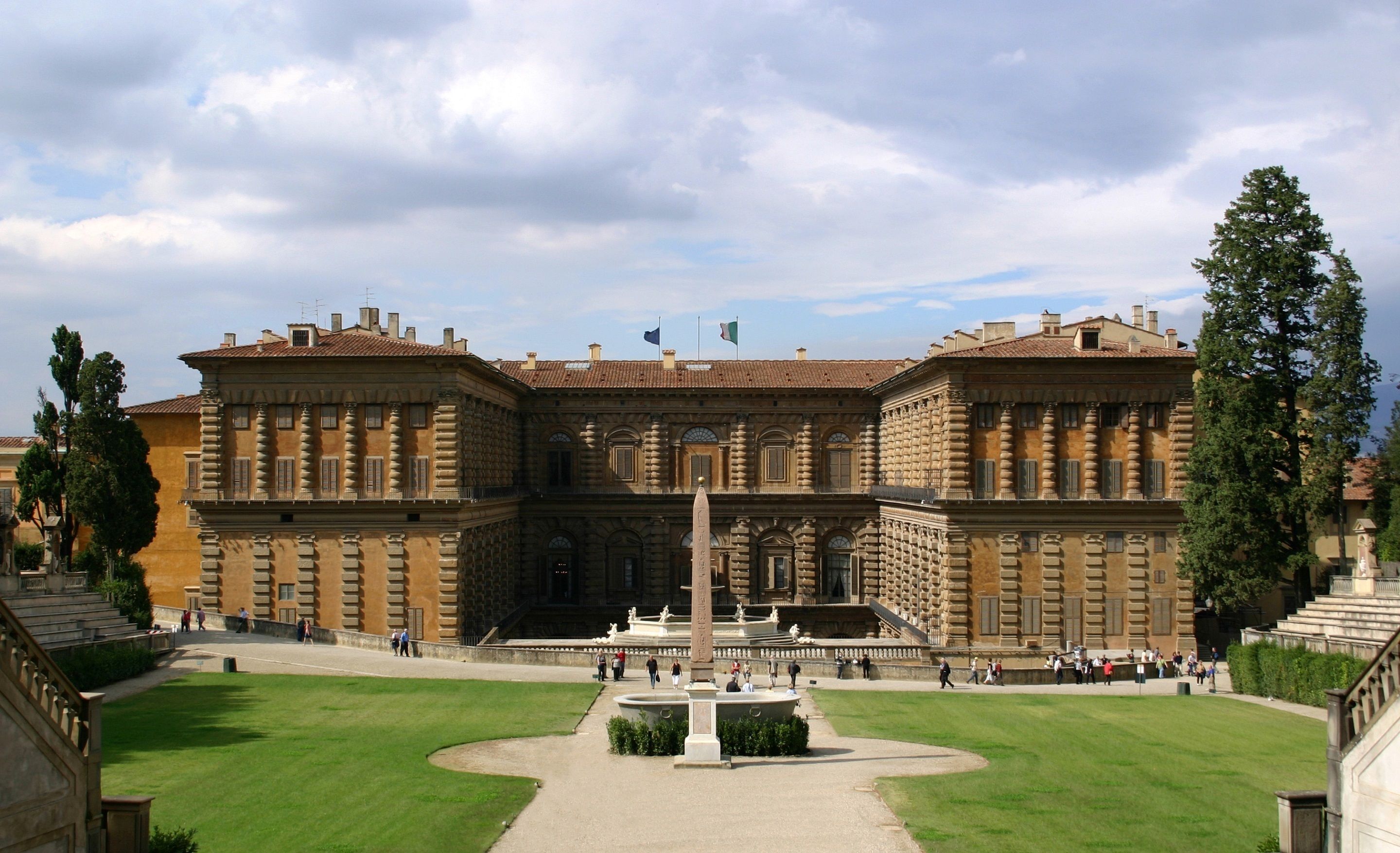 A large, historic building with a central courtyard, a fountain, and a statue.