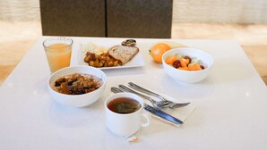 A breakfast table with various dishes, a glass of orange juice, a cup of tea, and a fireplace in the background. - Hyatt House Denver Downtown (Denver)