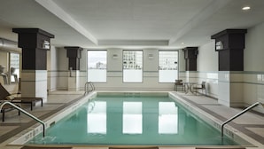 An indoor swimming pool with clear water, surrounded by tiled walls and benches.