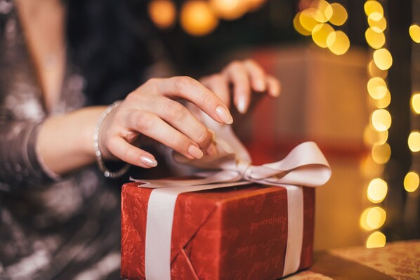 A hand placing a ribbon on a gift box. - Hyatt House Denver Downtown (Denver)