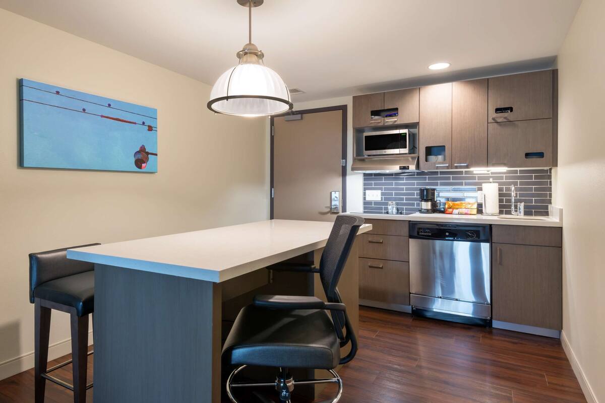A modern kitchen with a bar area, stainless steel appliances, and a blue and white color scheme.