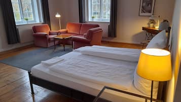 A hotel room with a bed, a desk, a chair, and two windows.