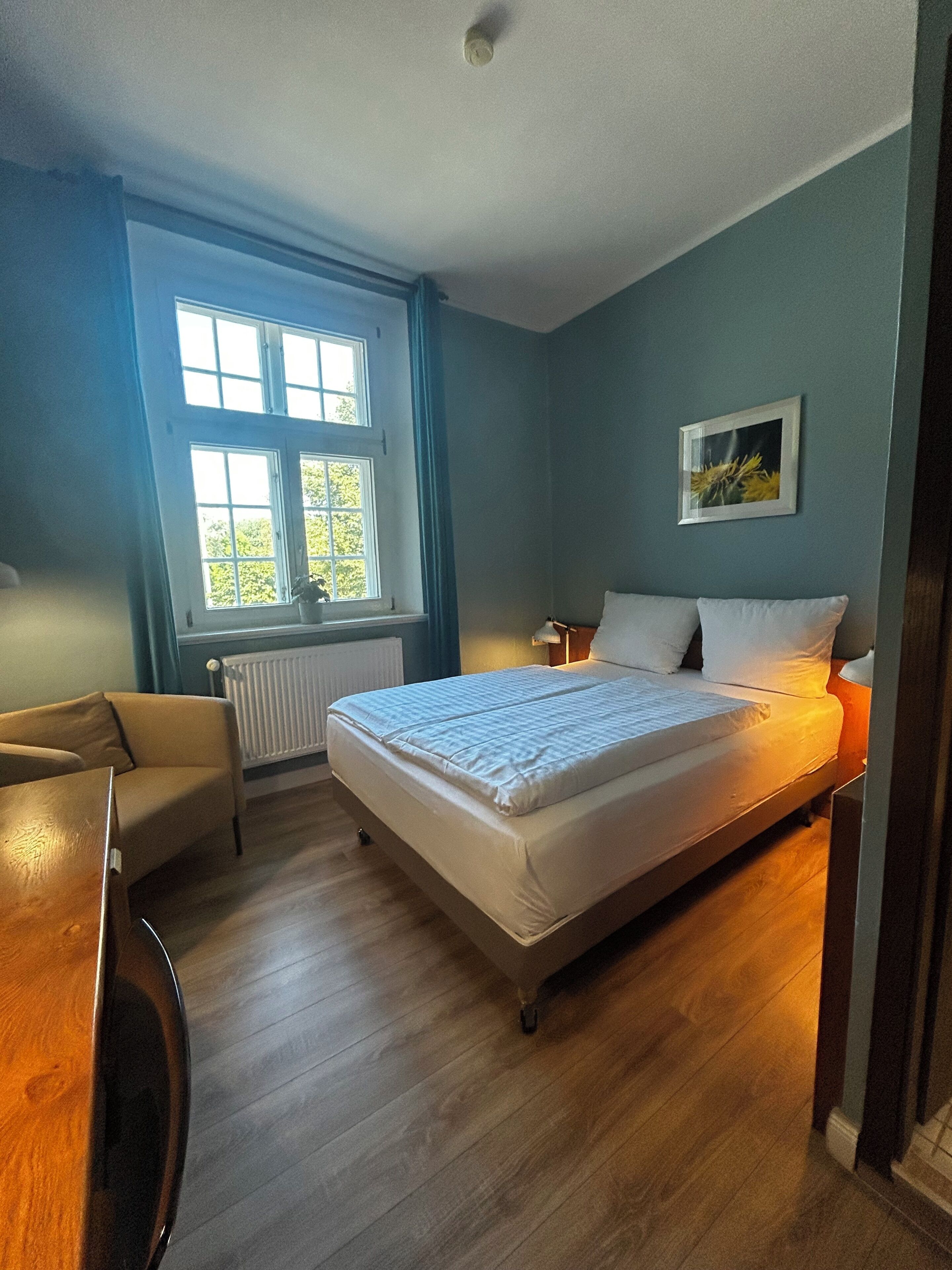 Ein Schlafzimmer mit Bett, Stuhl, Fenster und Heizkörper.