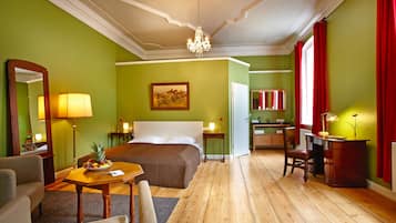 Een hotelkamer met een bed, een bureau, een stoel, een eettafel en een kroonluchter.