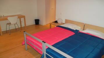 Un dormitorio con una cama, un escritorio y una silla.