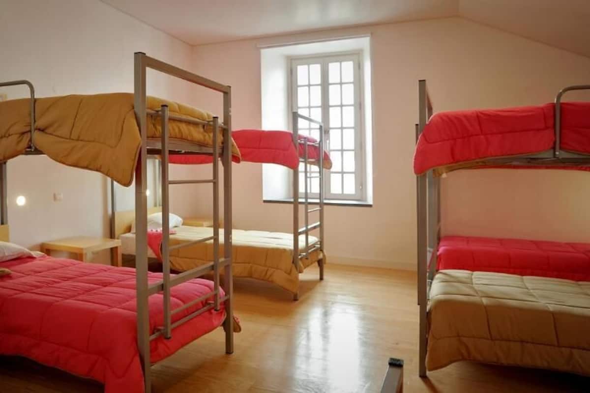 Un dormitorio con literas, una ventana y piso de madera.