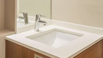 A modern bathroom with a white sink, chrome faucet, and a mirror above it.