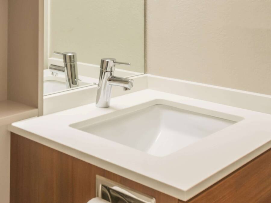 A modern bathroom with a white sink, chrome faucet, and a mirror above it.