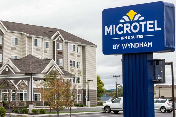 A Microtel Inn & Suites sign in front of a building with a covered entrance and a parking lot. - Microtel Inn & Suites By Wyndham Altoona (Altoona)