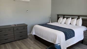 Un dormitorio con cama, cómoda, mesita de noche y un equipo de aire acondicionado.