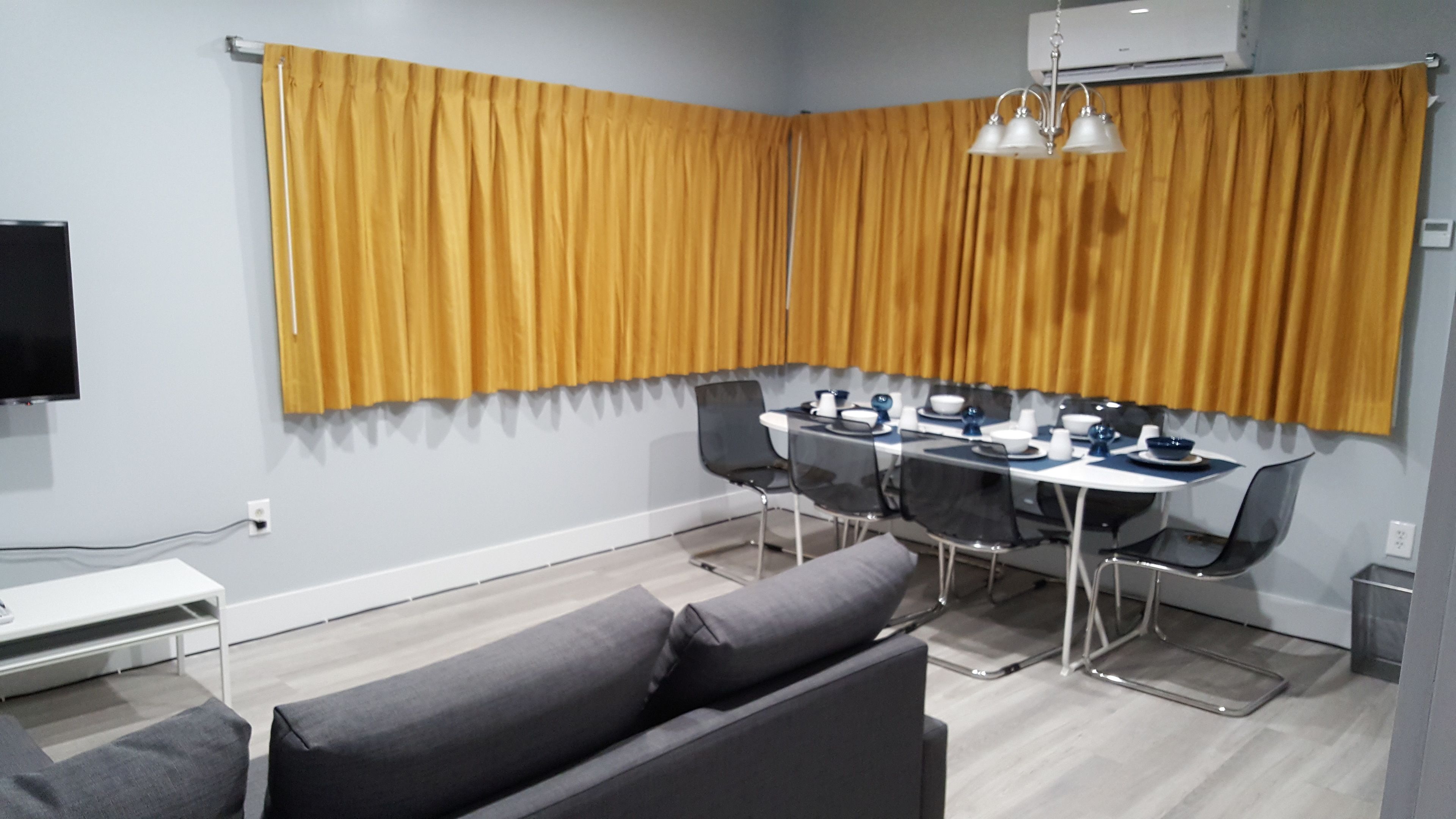 Une pièce moderne comprenant une table à manger, des chaises, un canapé et un téléviseur.