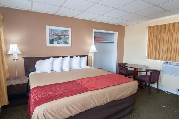 Quarto de hotel com cama, mesas de cabeceira, escrivaninha e cadeiras.