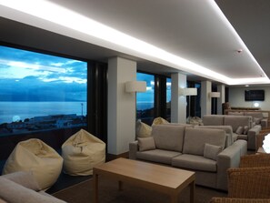 A modern hotel room with a large window offering a view of the sea and cityscape. - Azores Youth Hostels - São Jorge (Calheta)